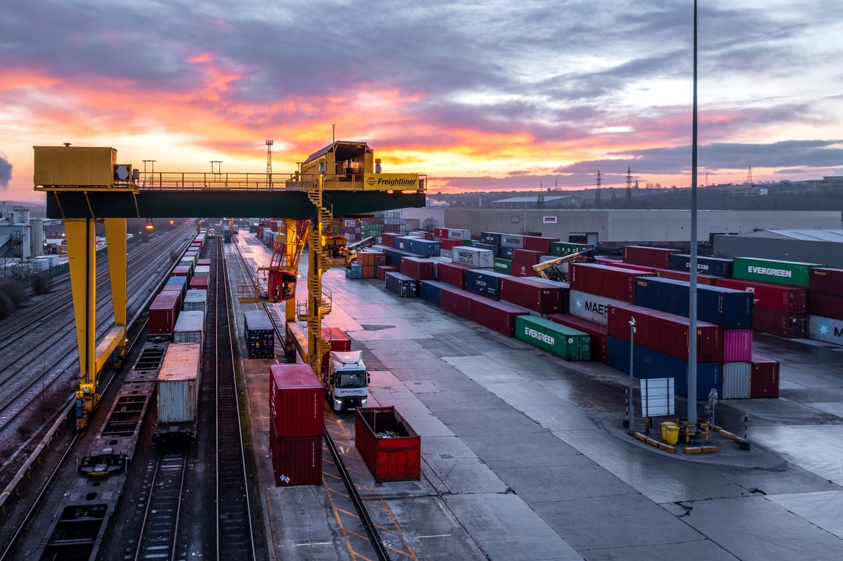 Aerial view of intermodal container terminal with freight trains at sunset