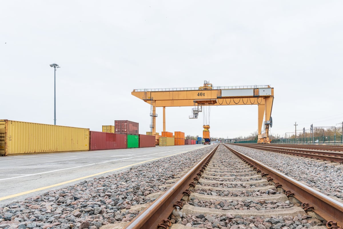 Modern intermodal logistics terminal with railway tracks and gantry crane loading shipping containers